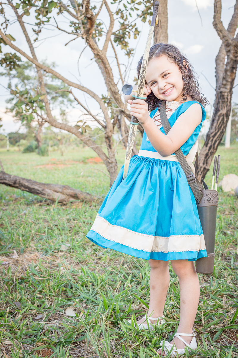 Ensaio infantil Valente Merida nossa filha Cecília arco e flecha diversão vestido azul