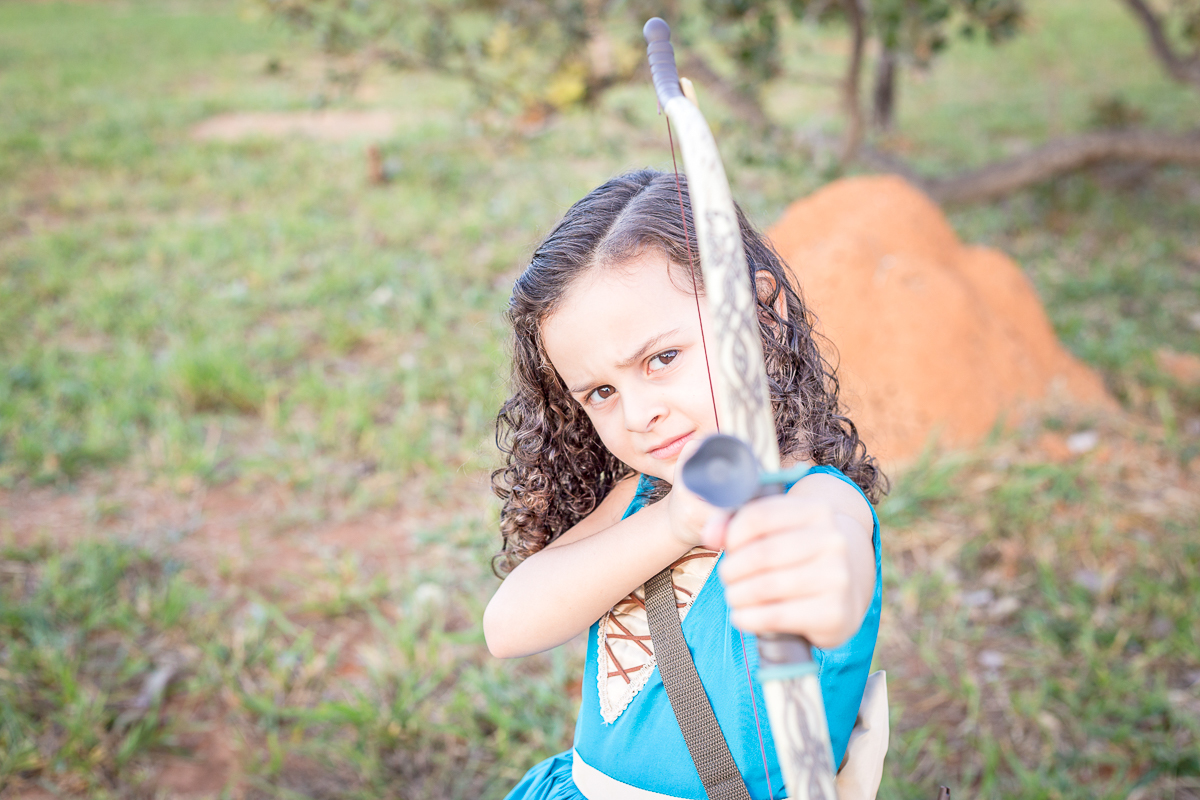 Ensaio infantil Valente Merida nossa filha Cecília arco e flecha diversão vestido azul