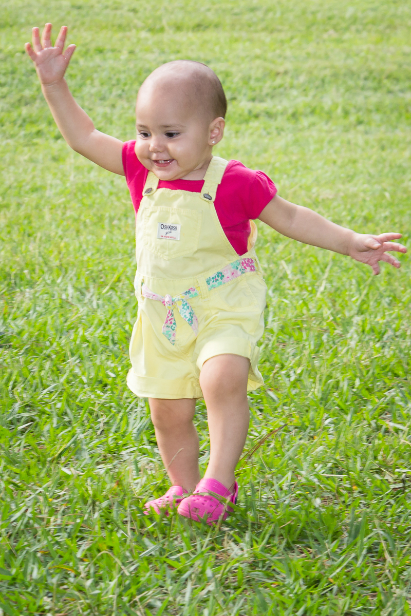 Lara bebê sorrindo andando na grama