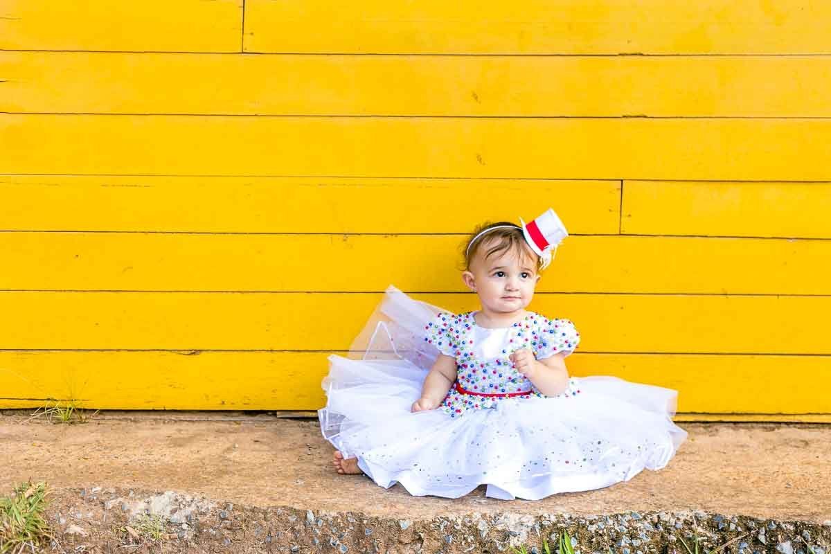 casinha amarela beb6e de vestido sentada no chão