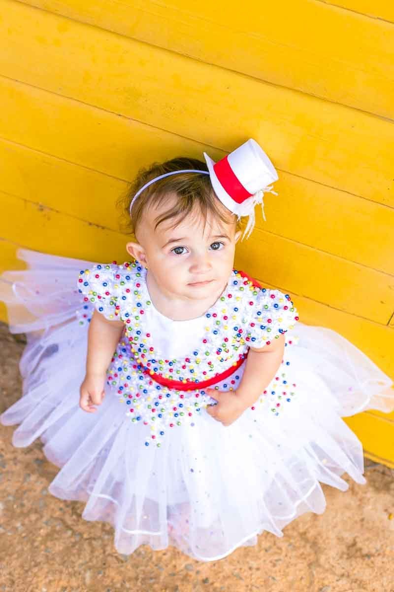 vestido branco salpicado de bolinhas coloridas cartola de mágico menina olhando