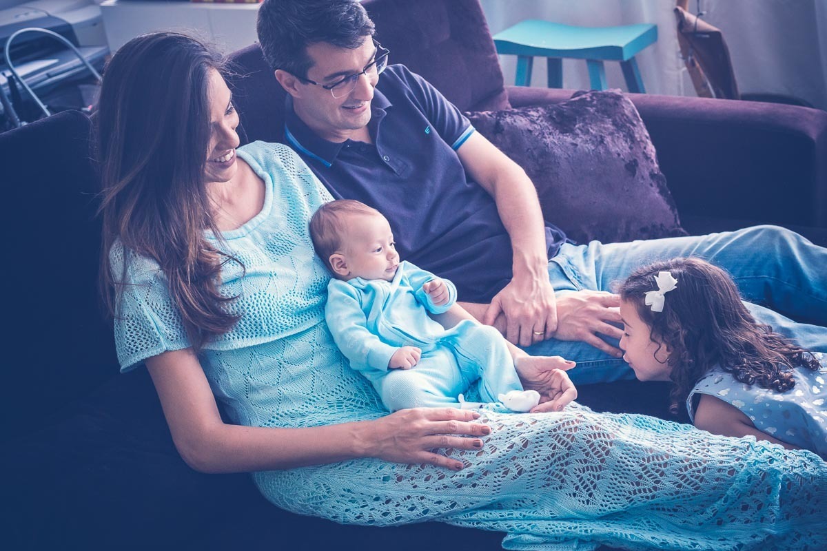 Família no sofá olhando o bebê