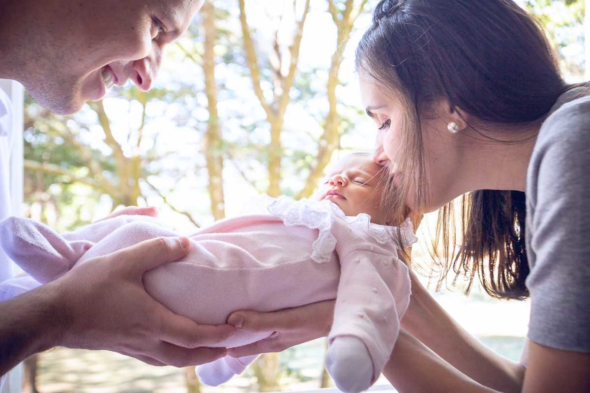 pais segurando a bebê mãe beijando a filha