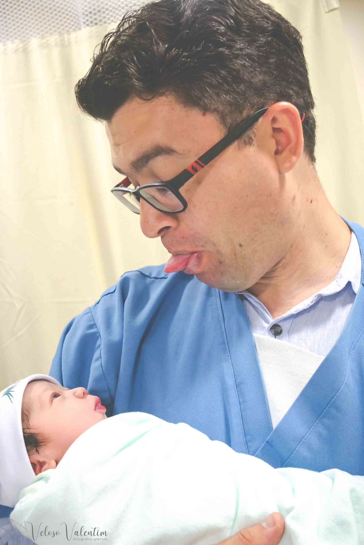 fotografia de parto fotógrafa de parto pai brincando com a filha no colo dando língua para ela parto natural hospitalar maternidade Brasília DF