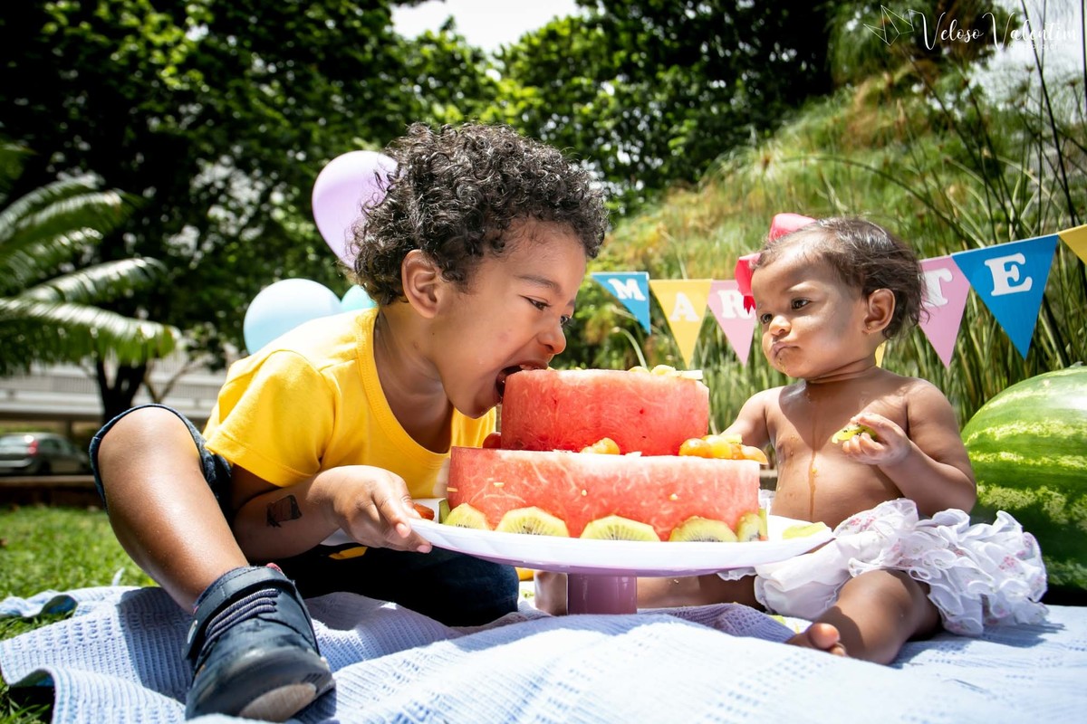 irmão atacando o bolo Ensaio smash the cake com bolo de frutas com a família em Brasília - DF