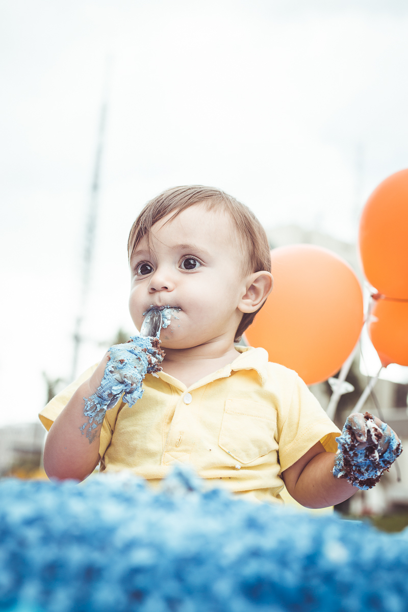 ensaio smash the cake tema foguete primeiro aninho parque da cidade família laranja e azul banho menino  Brasília DF veloso valentim book família fotografia bebê comendo bolo