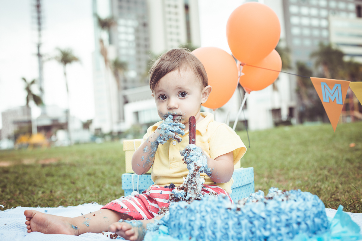 ensaio smash the cake tema foguete primeiro aninho parque da cidade família laranja e azul banho menino  Brasília DF veloso valentim book família fotografia bebê com bolo azul