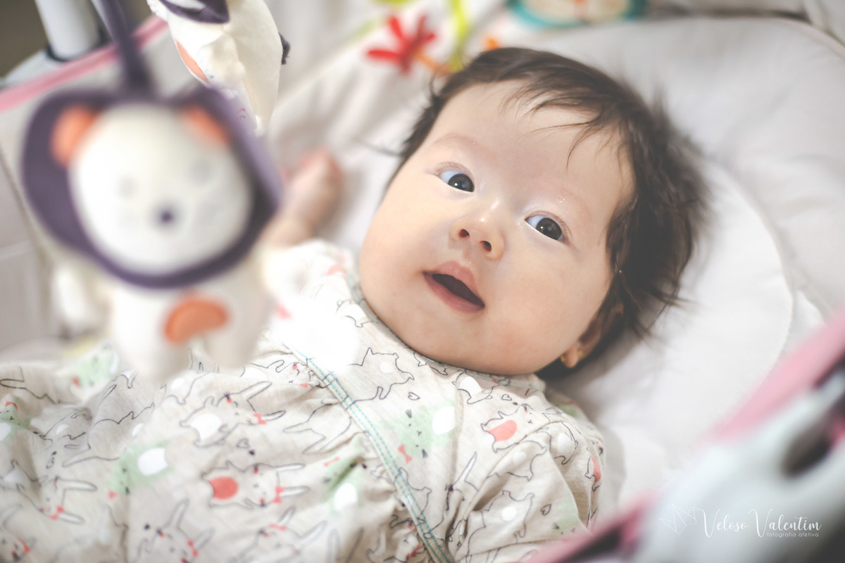 ensaio acompanhamento do primeiro ano do bebê Laura 3 meses em casa com a família ensaio lifestyle cotidiano Brasília DF Veloso Valentim fotografia afetiva bebê no berço com móbile menina oriental