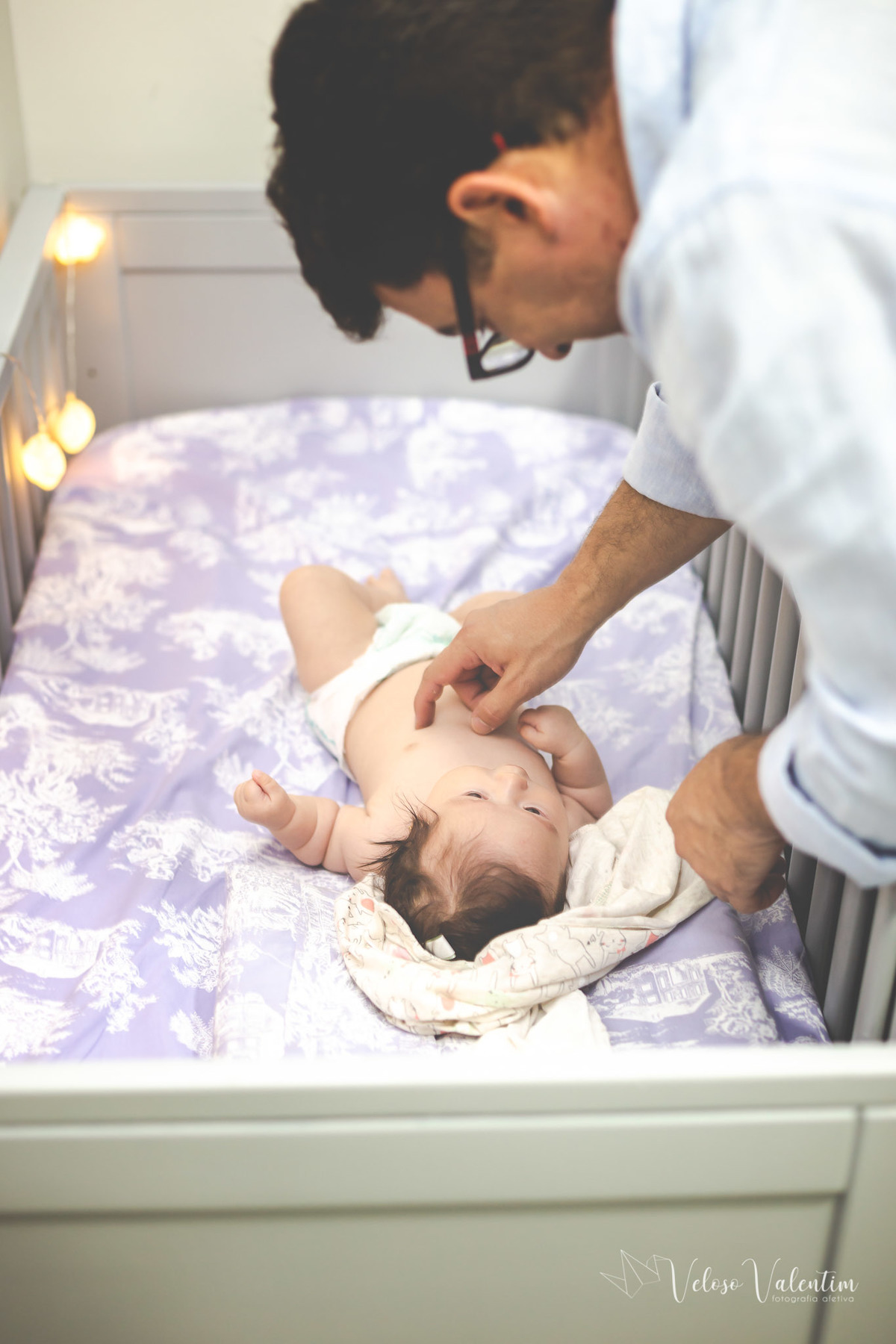 ensaio acompanhamento do primeiro ano do bebê Laura 3 meses em casa com a família ensaio lifestyle cotidiano Brasília DF Veloso Valentim fotografia afetiva bebê no berço recebendo carinho do pai menina oriental