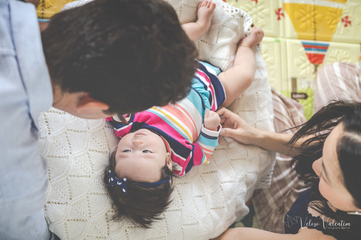 ensaio acompanhamento do primeiro ano do bebê Laura 3 meses em casa com a família ensaio lifestyle cotidiano Brasília DF Veloso Valentim fotografia afetiva família oriental pai e mãe olham a bebê deitada