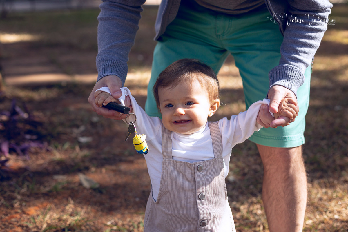 ensaio acompanhamento do primeiro ano do bebê Aurora 12 meses em casa com a família ao ar livre aprendendo a andar primeiros passos Brasília DF Veloso Valentim fotografia afetiva bebê andando na grama com o pai