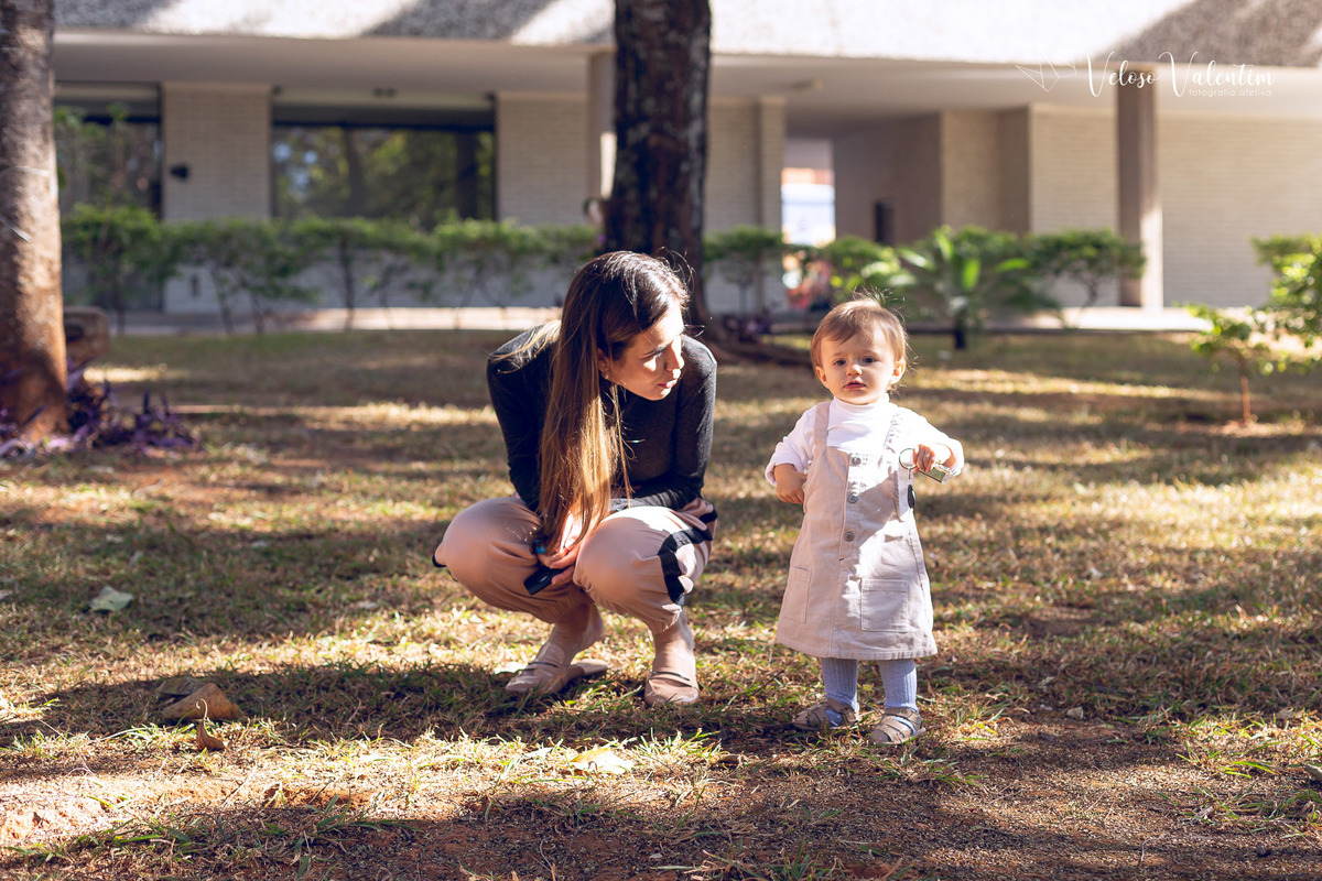 ensaio acompanhamento do primeiro ano do bebê Aurora 12 meses em casa com a família ao ar livre aprendendo a andar primeiros passos Brasília DF Veloso Valentim fotografia afetiva bebê andando na grama com a mãe