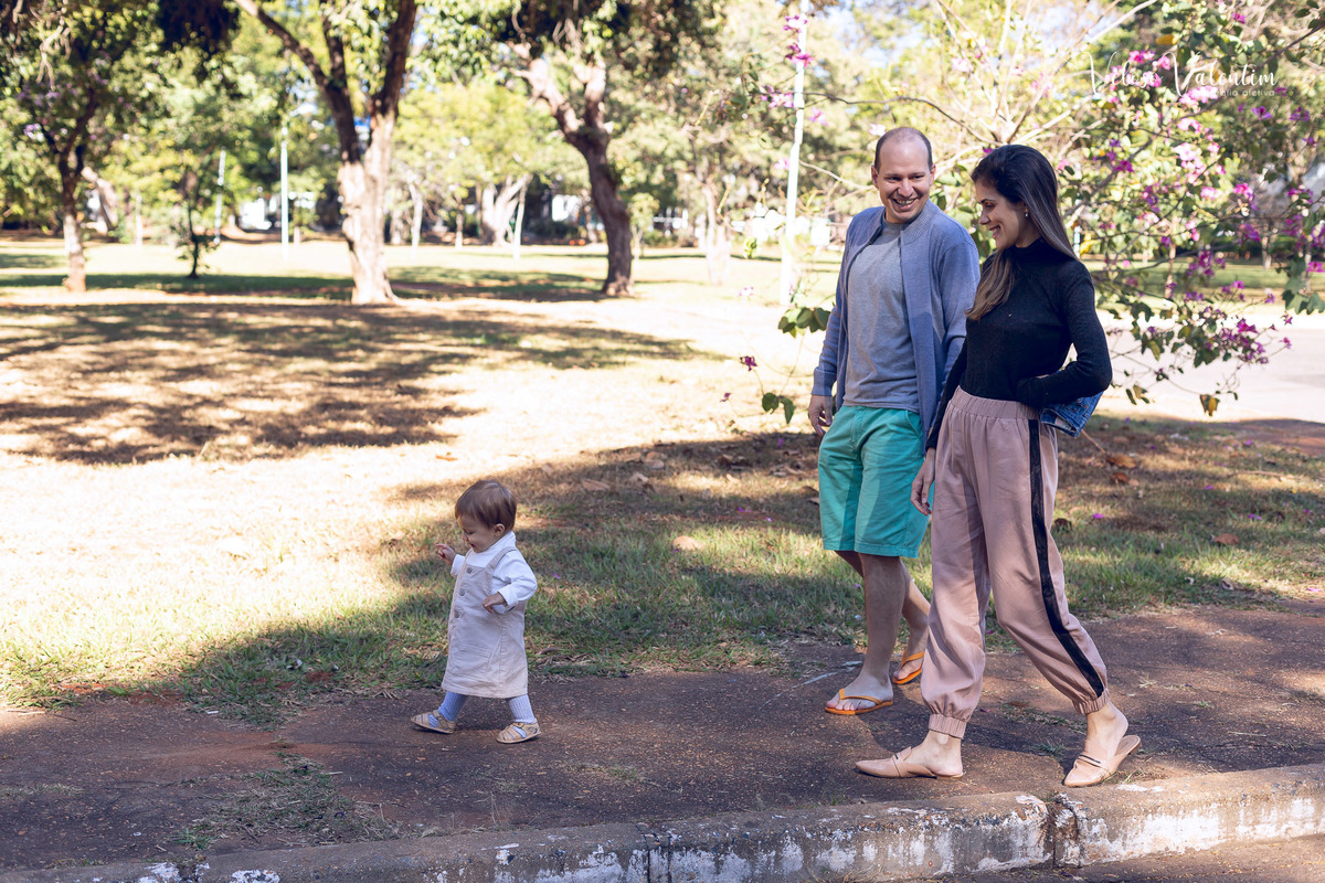 ensaio acompanhamento do primeiro ano do bebê Aurora 12 meses em casa com a família ao ar livre aprendendo a andar primeiros passos Brasília DF Veloso Valentim fotografia afetiva bebê andando na calçada com os pais