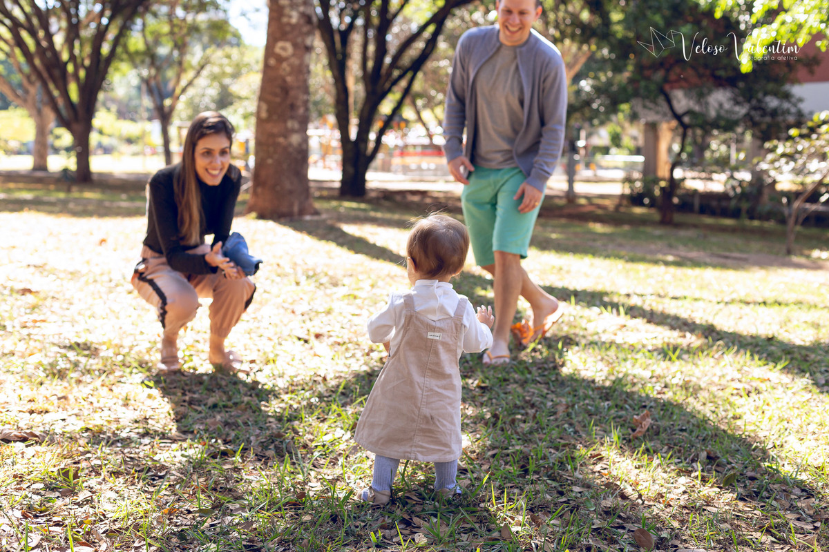ensaio acompanhamento do primeiro ano do bebê Aurora 12 meses em casa com a família ao ar livre aprendendo a andar primeiros passos Brasília DF Veloso Valentim fotografia afetiva bebê andando na na grama brincando com os pais