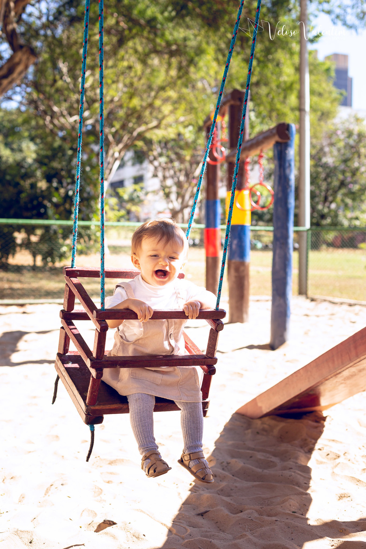 ensaio acompanhamento do primeiro ano do bebê Aurora 12 meses em casa com a família ao ar livre aprendendo a andar primeiros passos Brasília DF Veloso Valentim fotografia afetiva bebê no balanço do parquinho sorrindo