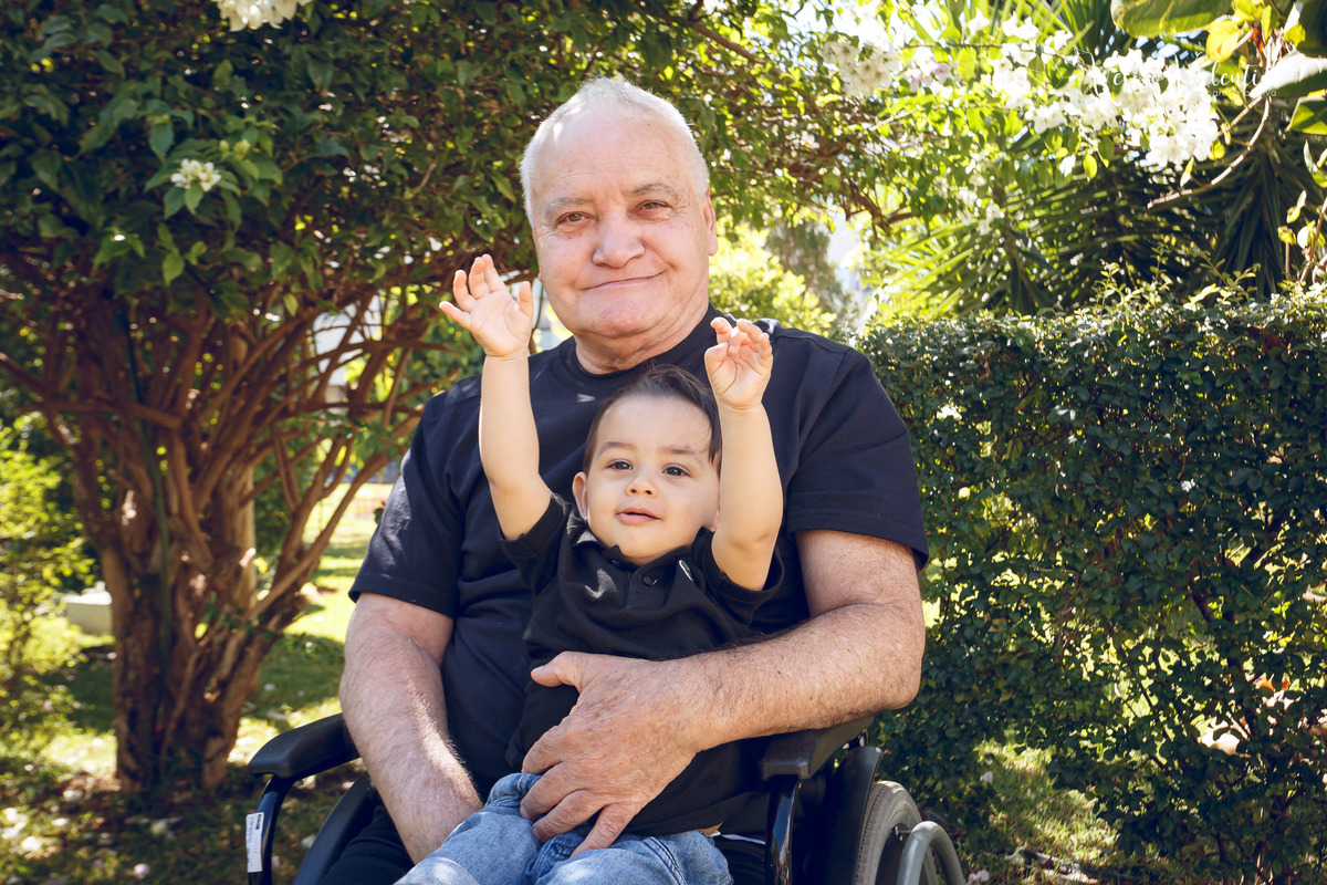 ensaio acompanhamento do primeiro ano do bebê Gabriel 12 meses em casa com a família ao ar livre engatinhando pai mãe avós ensaio família acompanhamento mensal fotográfico Brasília DF avô cadeira de rodas