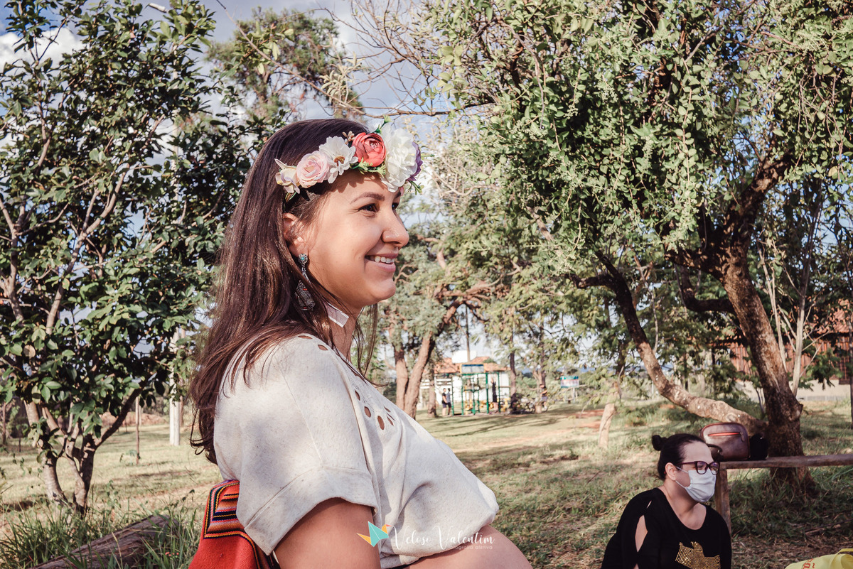 gestante sorrindo com coroa de flores ao ar livre