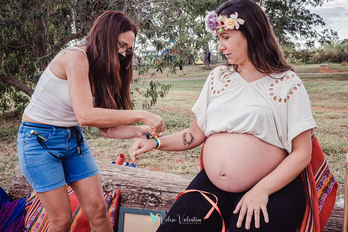 mãe amarra fita no braço da filha gestante