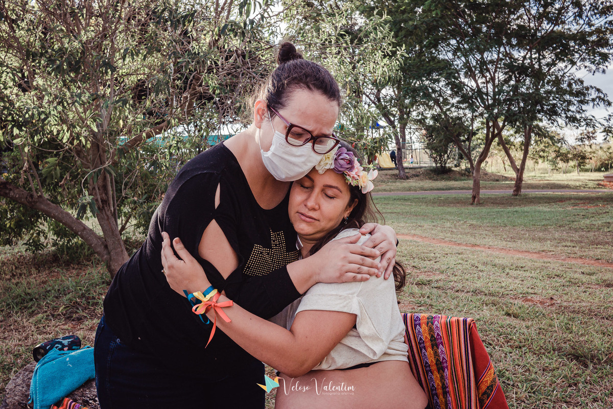 mulher de máscara abraça gestante sentada