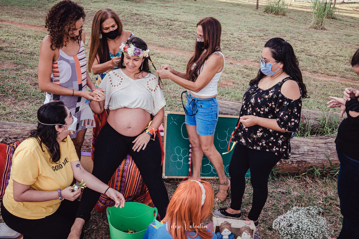 mulheres trançando o cabelo e fazendo massagem em uma grávida