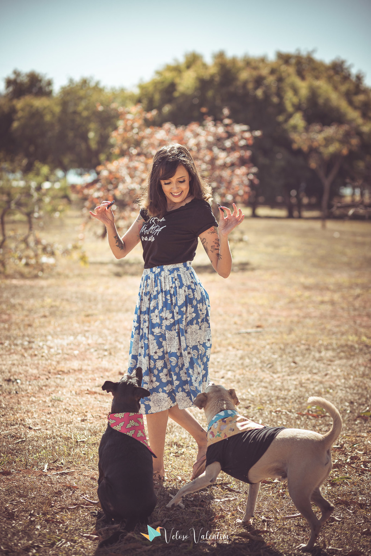 mulher de saia estampada brincando com cachorros