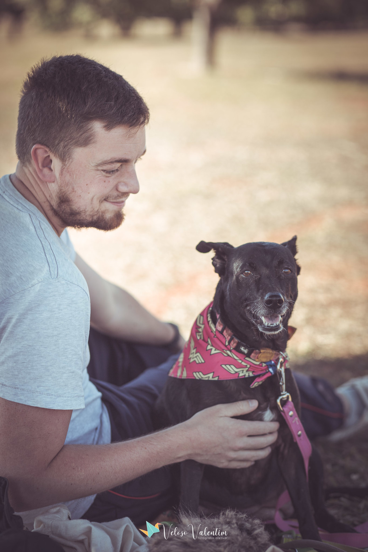 cachorro preto com bandana e homem sentado