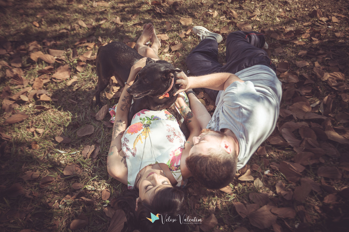 casal deitado no chão de folhas secas com cachorro