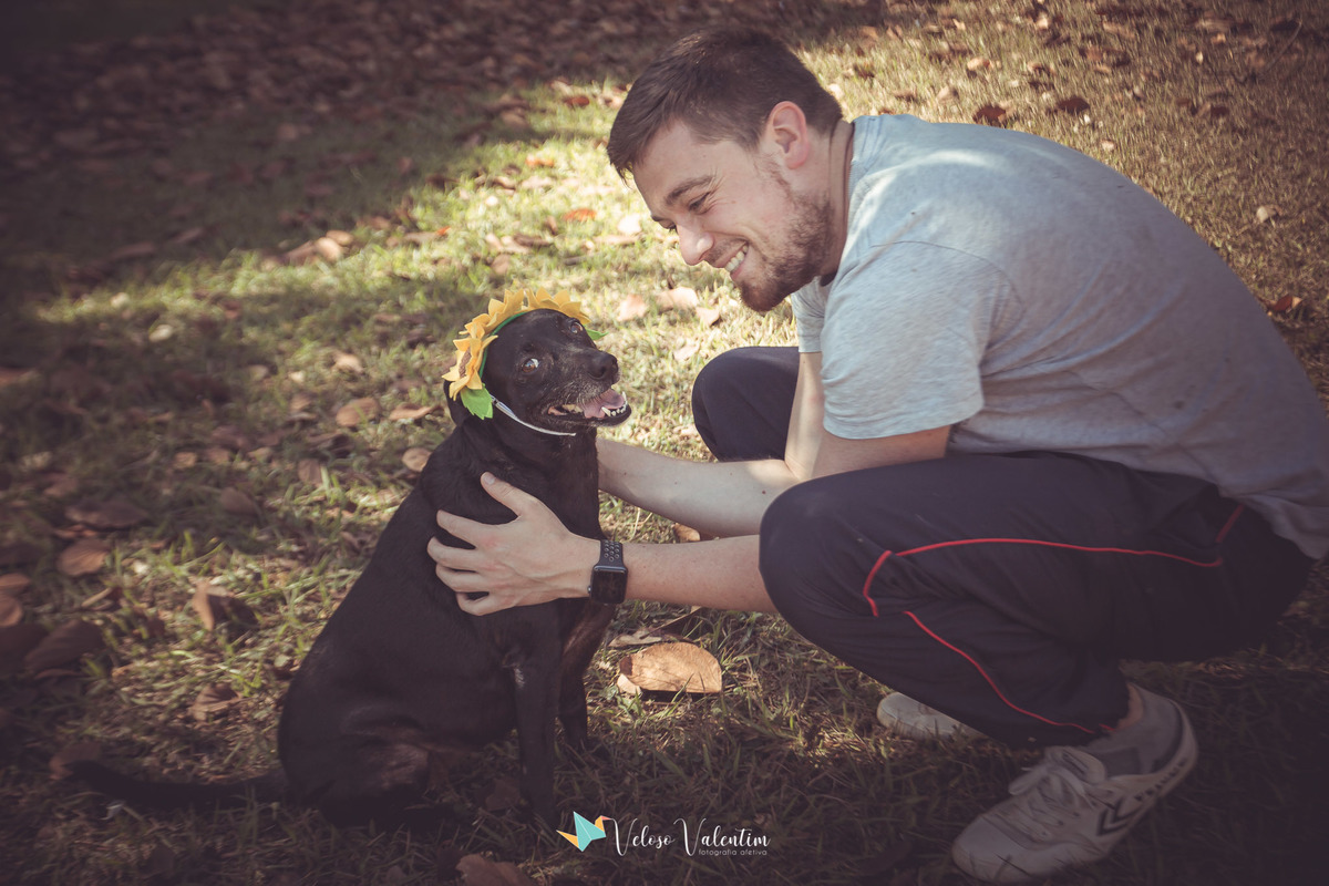 homem com cachorro preto com coroa de flores amarelas