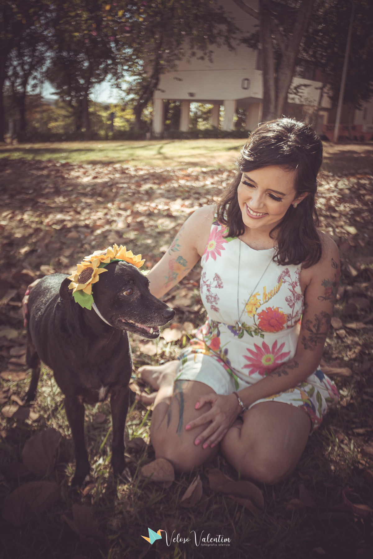 mulher com cachorro preto com coroa de flores amarelas