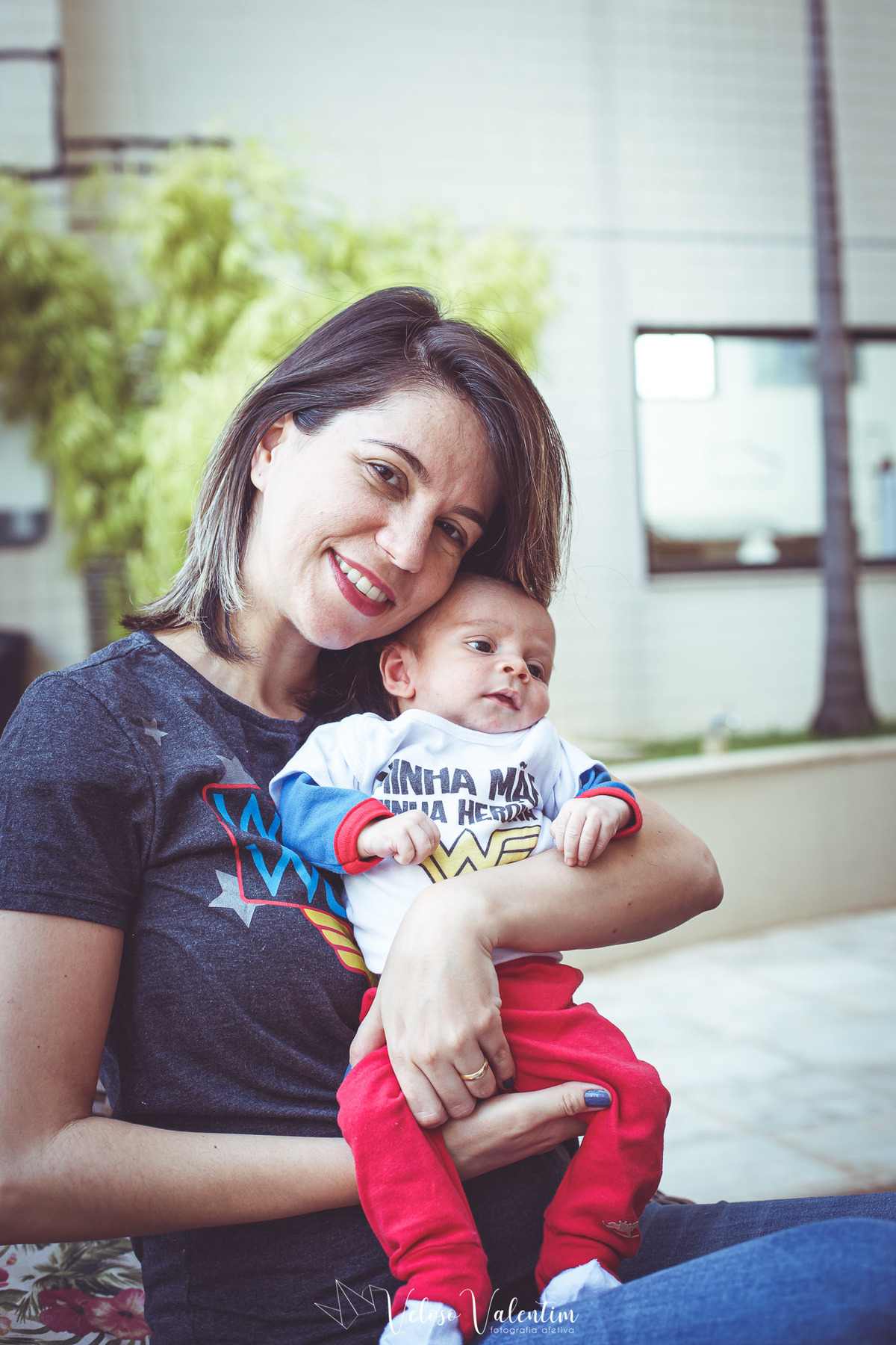 mãe com camiseta de mulher maravilha segura filho no colo