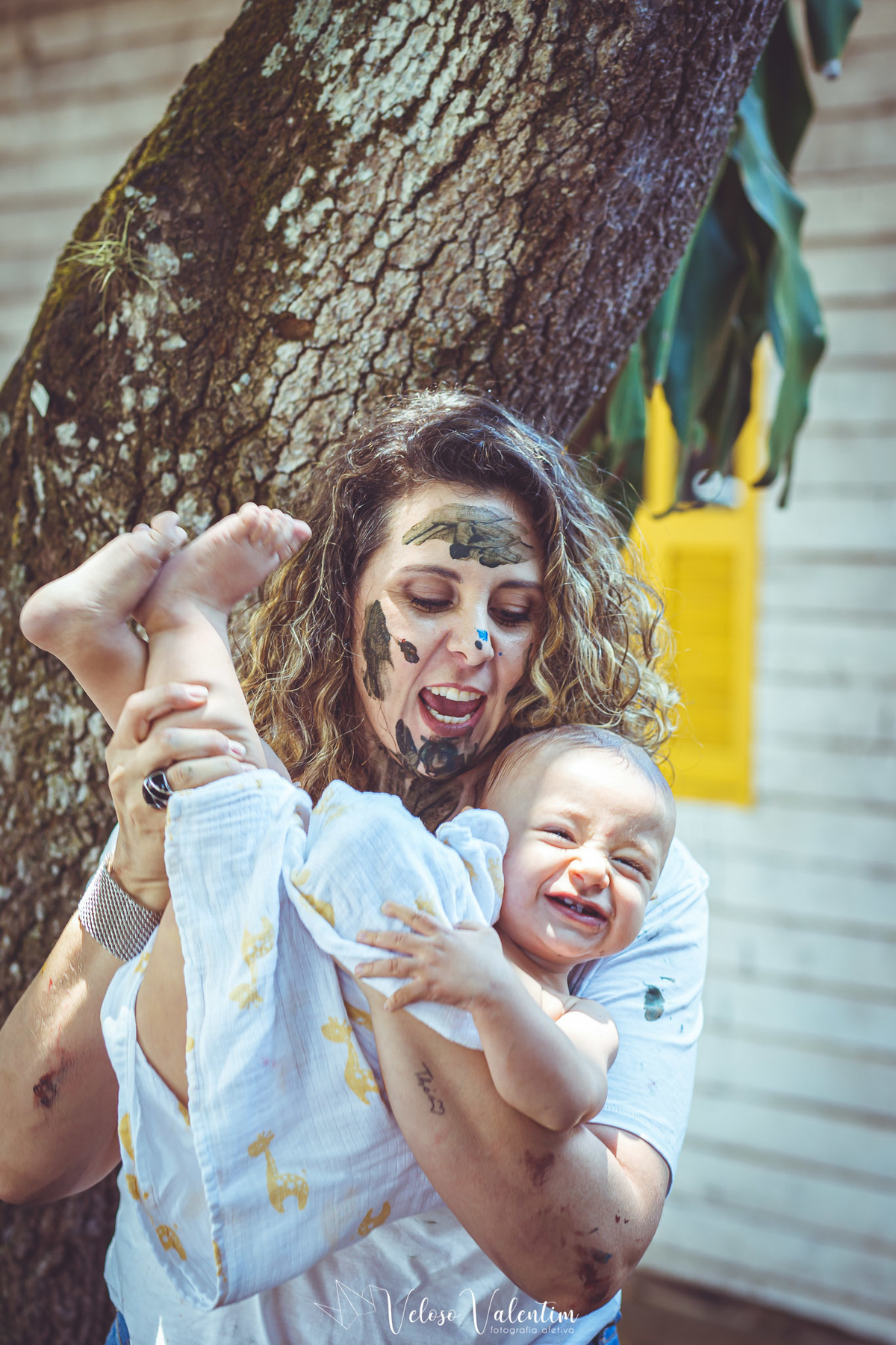 mãe brinca com o filho enrolado na toalha