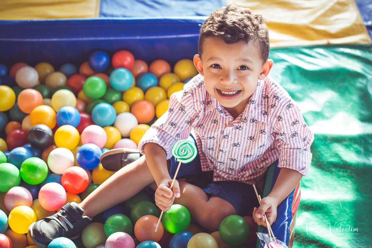 menino com pirulito na piscina de bolinhas