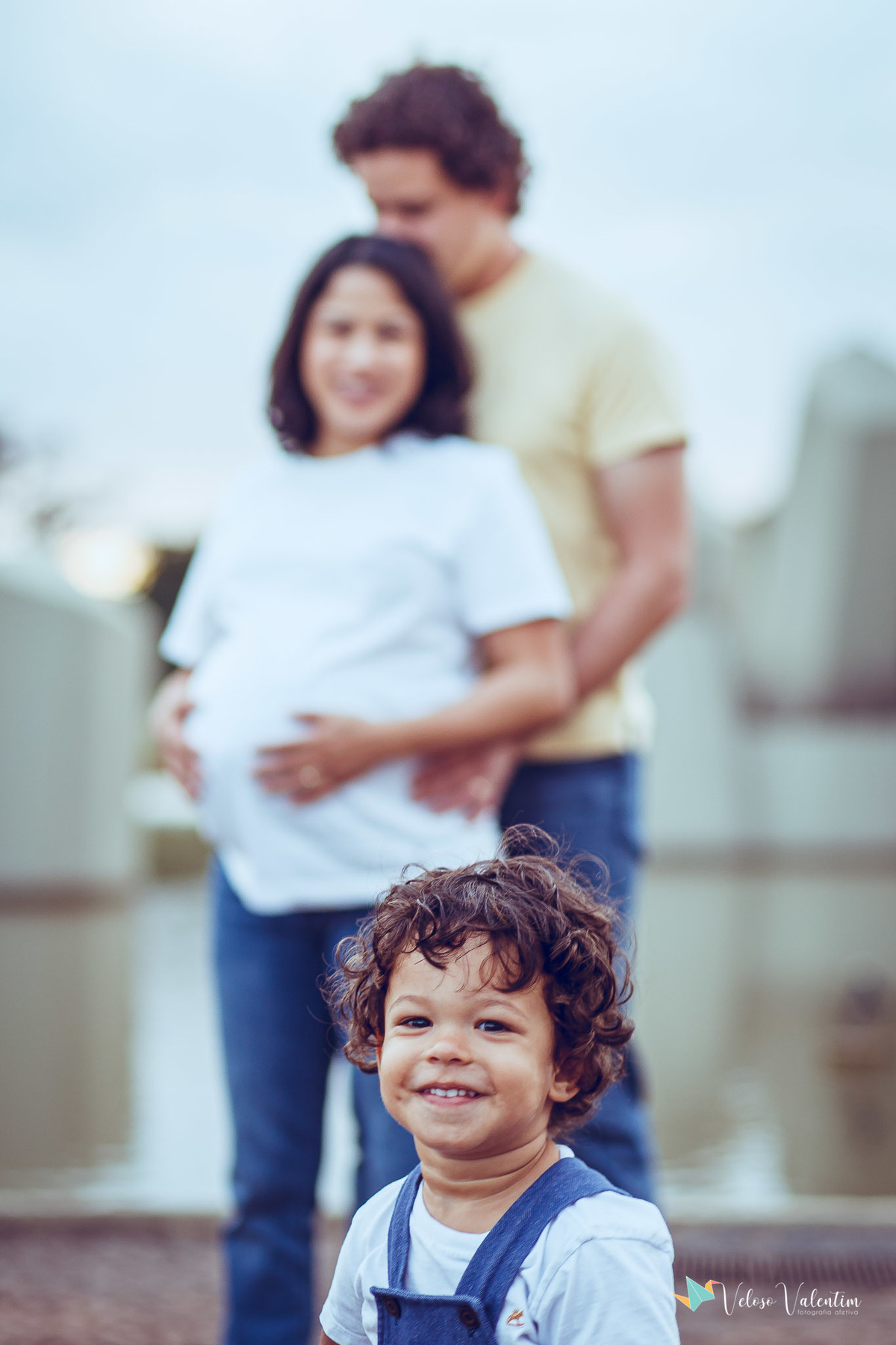 menino em primeiro plano com os pais no fundo