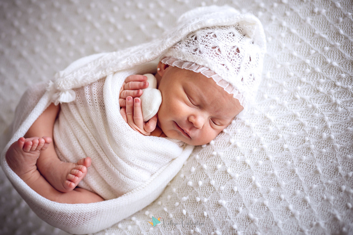 bebê deitada dormindo sorrindo abraçada a um coraçãozinho ensaio newborn em casa Brasília