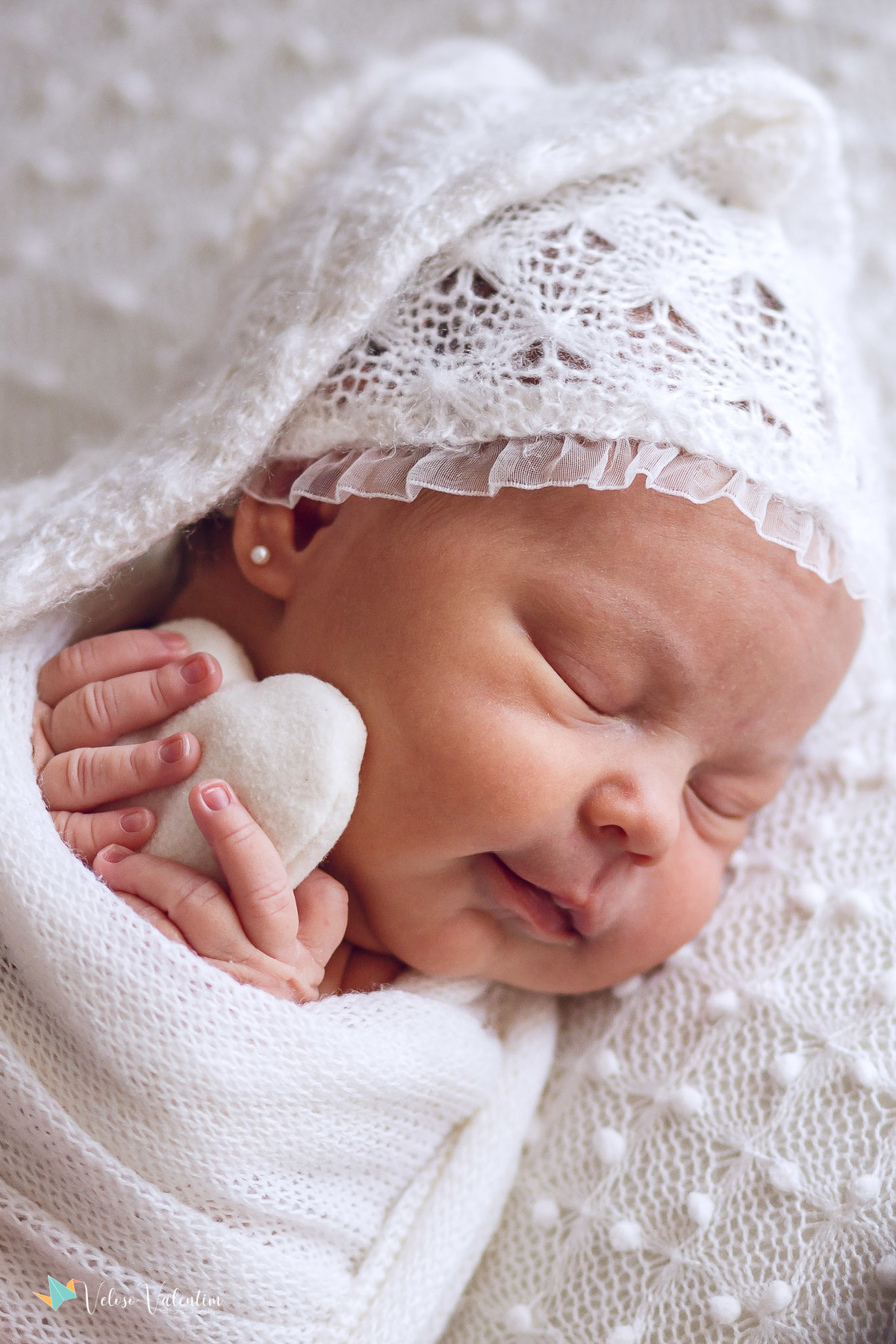 close no rosto bebê deitada dormindo abraçada a um coraçãozinho ensaio newborn em casa Brasília