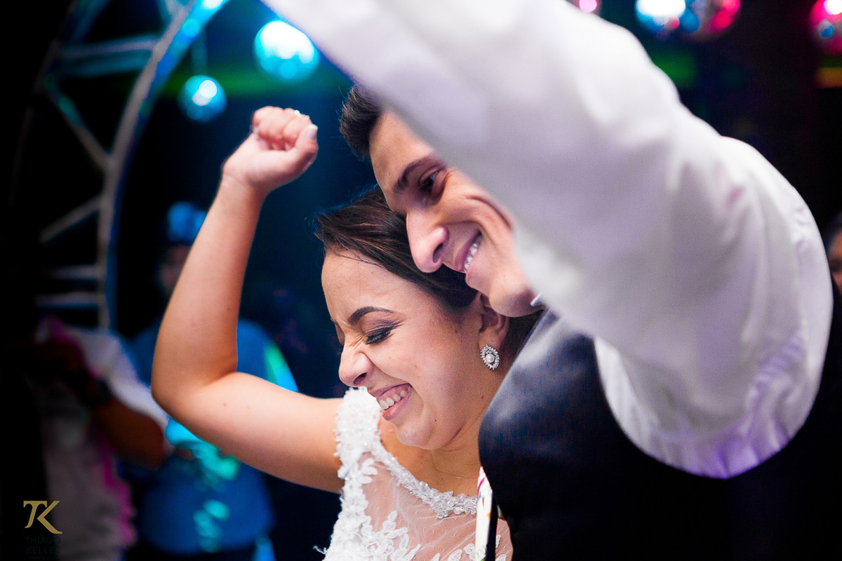 Foto dos noivos se divertindo durante a festa realizada no salão do Jóquei Clube.