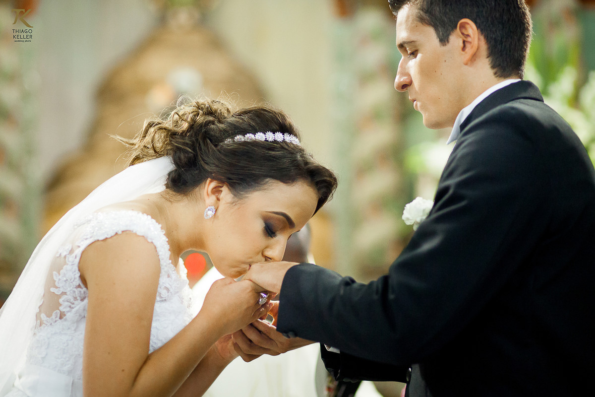 Foto da noiva beijando a aliança do noivo em frente ao alter da Igreja do Rosário.