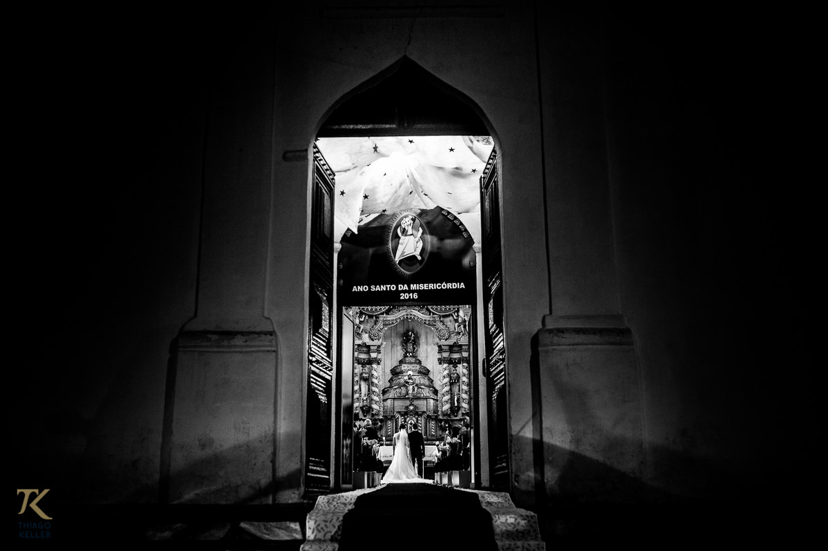 Casamento de Sabrina e Alisson. Vista externa do altar com noivos recebendo as bençãos do padre.