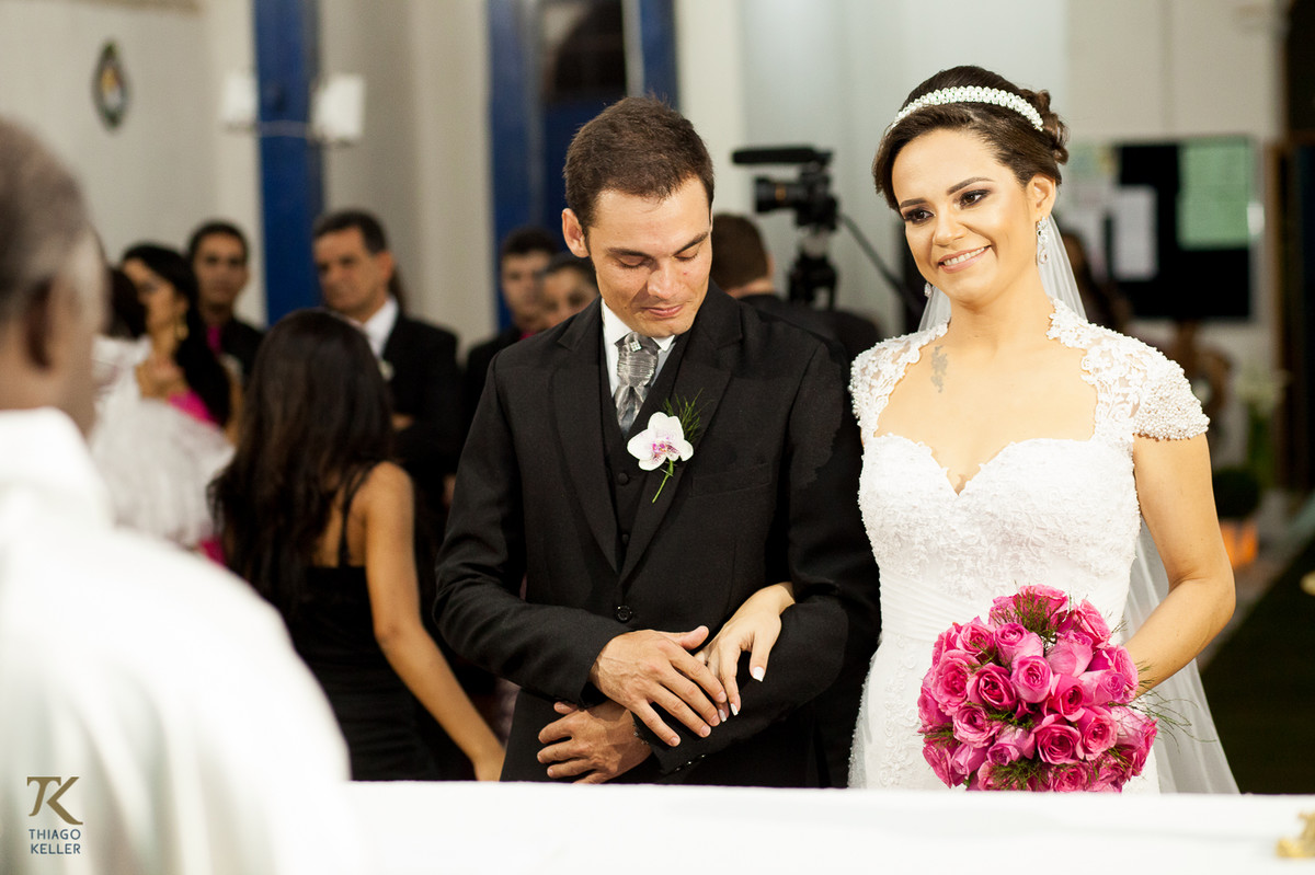 Casamento de Sabrina e Alisson. Noivo faz carinho nas mãos da noiva em frente ao altar.