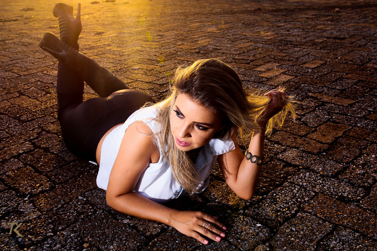 ensaio fotográfico book de Jackeline Marins realizado na cidade de Paracatu, Minas Gerais com a modelo vestindo uma calça de couro e deitada contra luz.