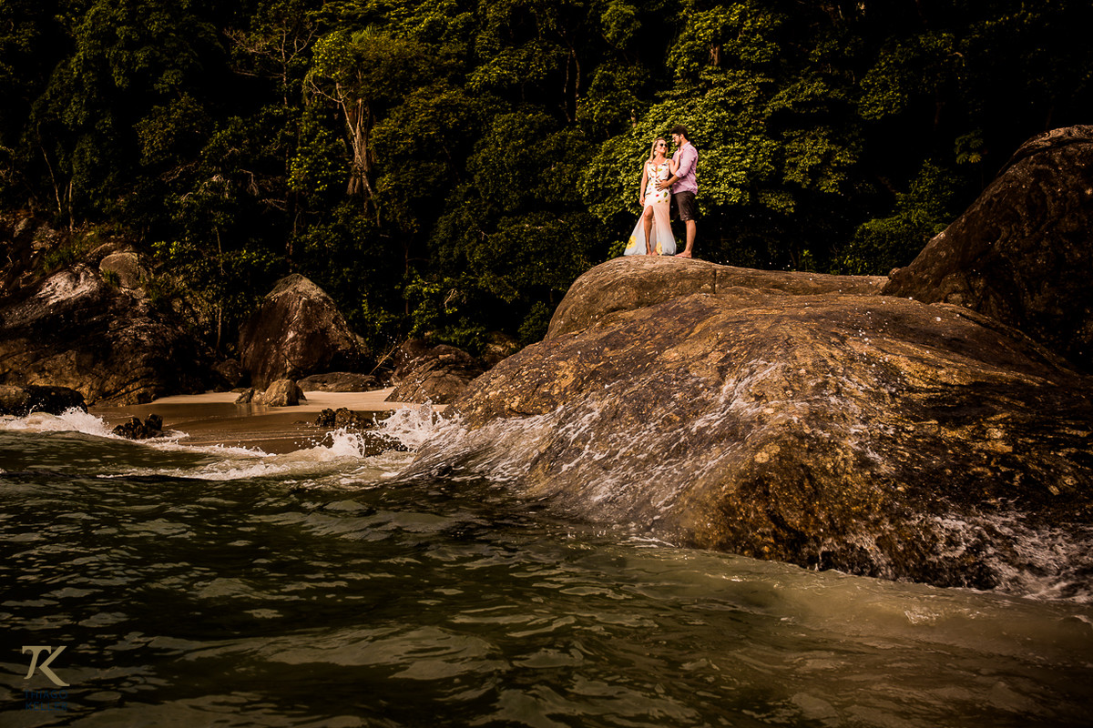 Casal em pé, de frente ao mar, na ilha da Baleia, no Balneário de Maresias em São Paulo.