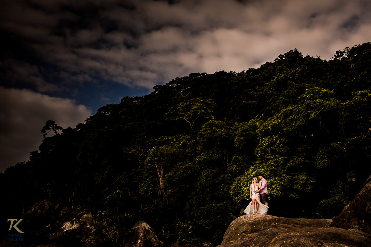 Casal em pé, de frente ao mar, na ilha da Baleia, no Balneário de Maresias em São Paulo.