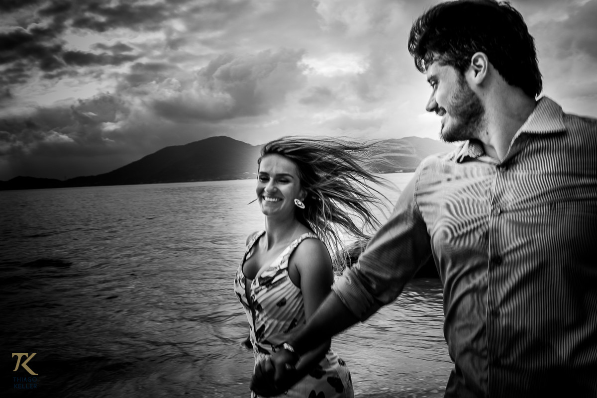 Casal correndo na praia e se olhando. Foto em preto e branco.