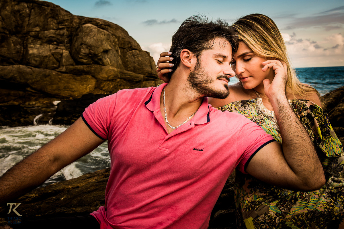 Casal se acaricia e atrás deles o mar de Maresias.