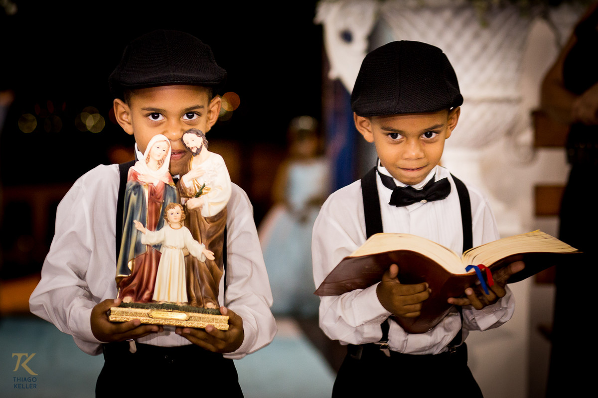 Fotografia de casamento de Lívia e Paulo Henrique na cidade de Paracatu, Minas Gerais. Pajens entram carregando a bíblia e nosso senhor Jesus Cristo.
