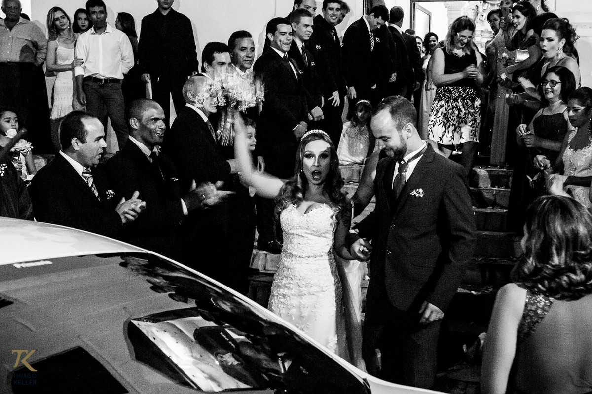 Fotografia de casamento de Lívia e Paulo Henrique na cidade de Paracatu, Minas Gerais. Casal comemora na saída da Igreja. Foto em Preto e Branco.