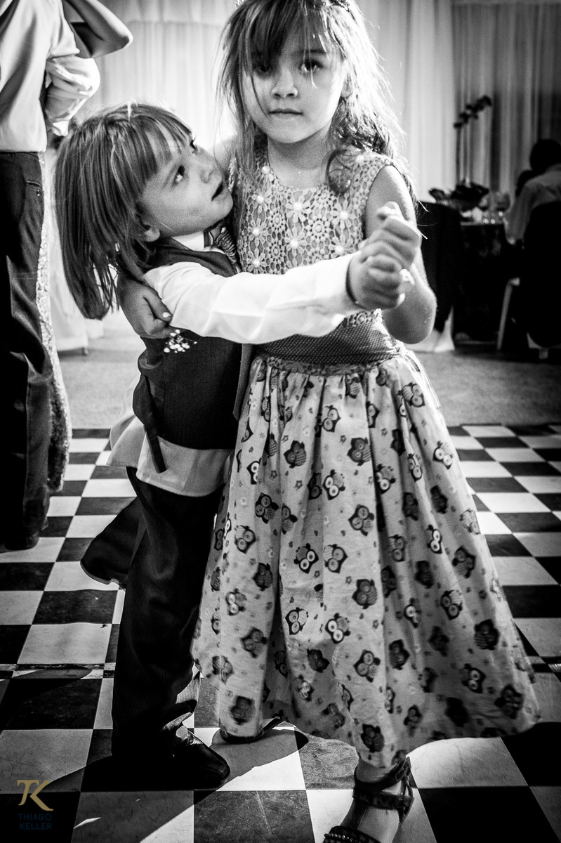 Fotografia de casamento de Lívia e Paulo Henrique na cidade de Paracatu, Minas Gerais. Casal de pajem e dama dançam na pista.