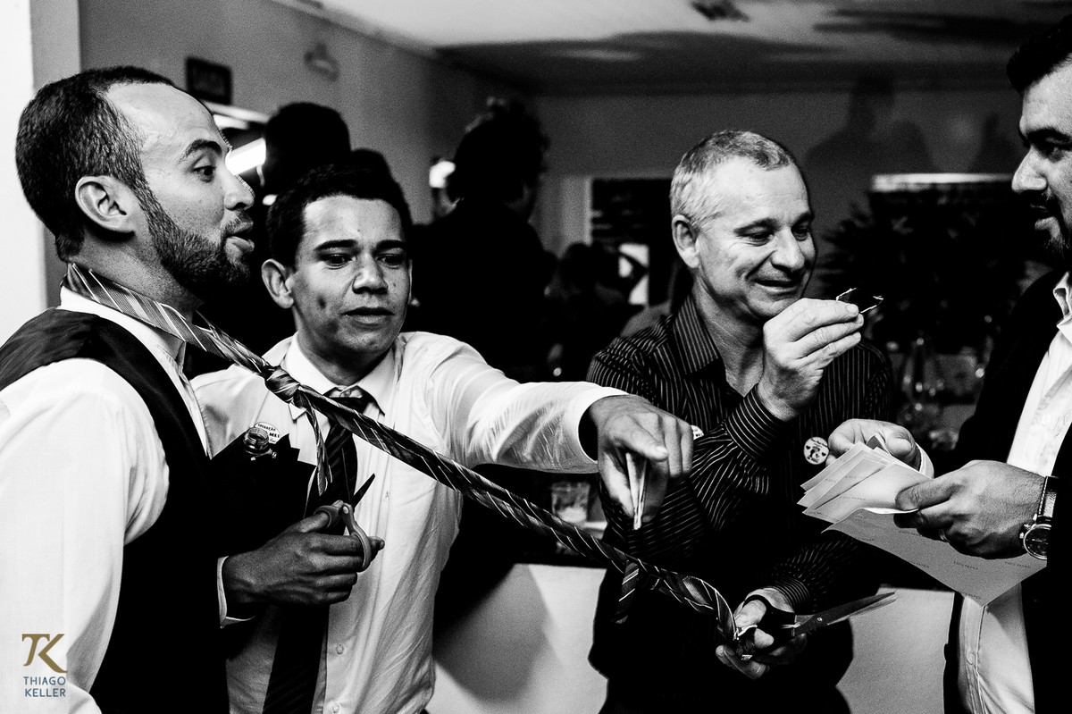 Fotografia de casamento de Lívia e Paulo Henrique na cidade de Paracatu, Minas Gerais. Noivo animado durante a passagem da gravata. Foto em preto e branco.