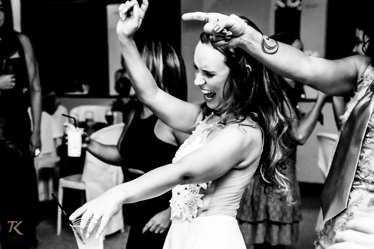 Fotografia de casamento de Lívia e Paulo Henrique na cidade de Paracatu, Minas Gerais. Noiva animada na pista de dança. Foto em preto e branco.