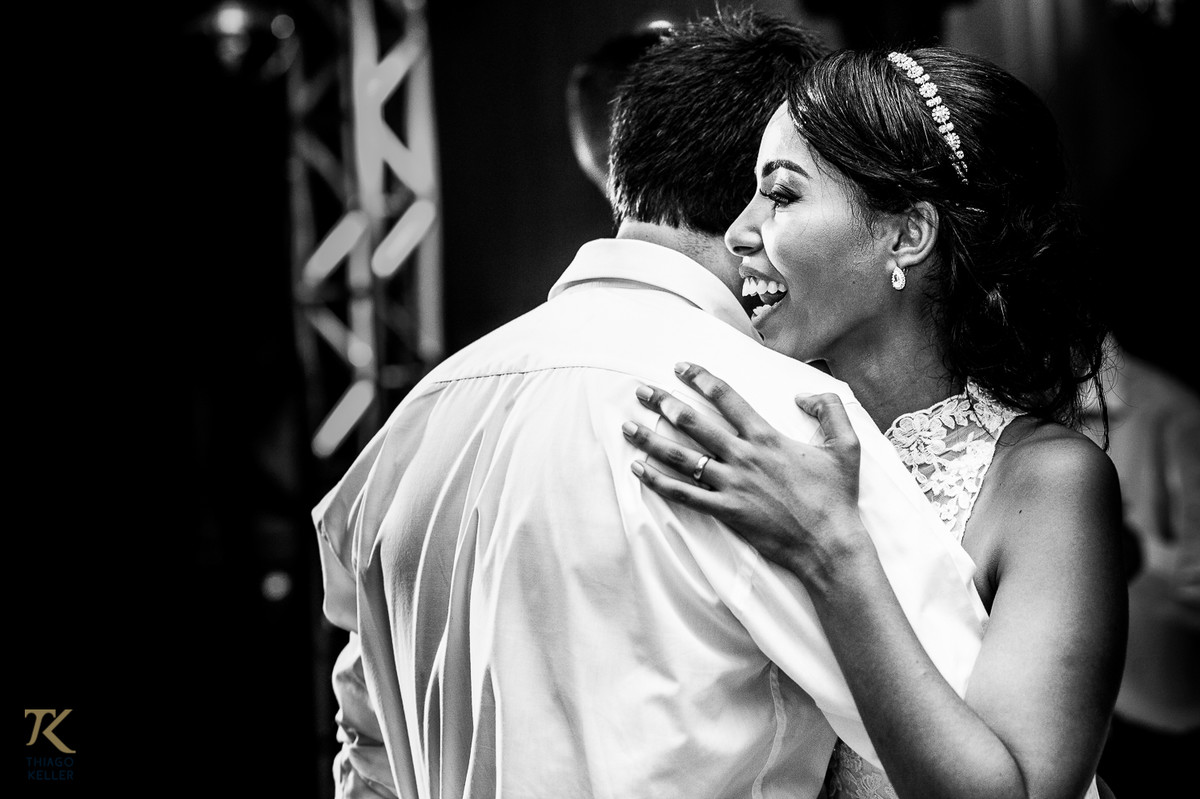 Fotografia de Casamento de Maura e Thiago realizado na cidade de Paracatu, Minas Gerais. Noivos dançam coladinhos. Foto em preto e branco.